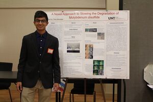 Dave Banerjee standing next to his research paper at TAMS Fair